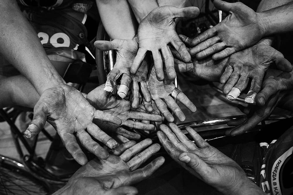Wheelchair basketball players hold out their worn and taped hands.